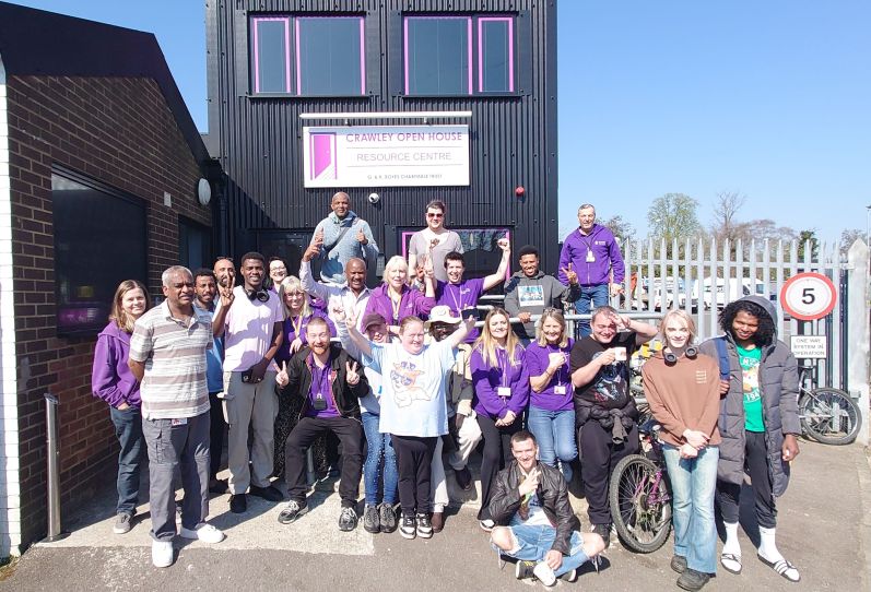 A number of service users hvaing a photo op with staff outside the Resource Centre on a sunny summer afternoon